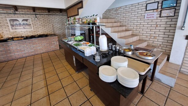 Mesa de buffet con diferentes alimentos y salsas, una escalera, y un letrero que indica acceso restringido.