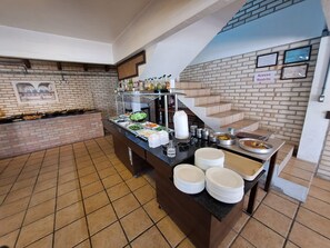 Mesa de buffet con diferentes alimentos y salsas, una escalera, y un letrero que indica acceso restringido.