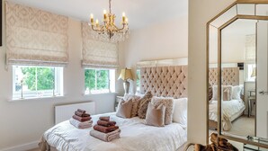 Une chambre à coucher avec un grand lit, un lustre et un miroir.