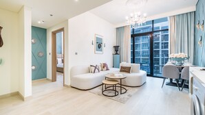 Ein modernes Wohnzimmer mit einem weißen Sofa, einem runden Couchtisch und einem Essbereich mit Tisch und Stühlen.