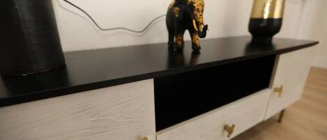 A black and white cabinet with gold handles, a black object on the left, and a golden vase on the right.