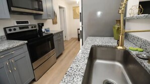 A kitchen with granite countertops, stainless steel appliances, and a gold faucet.