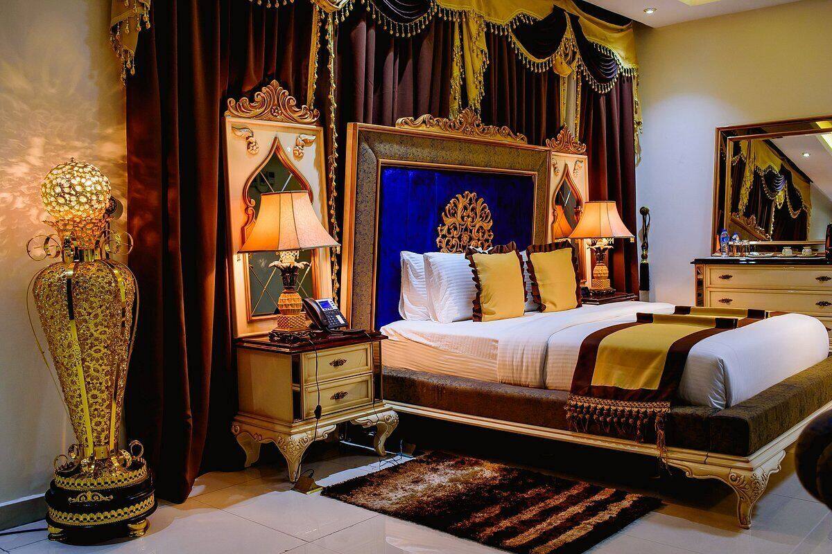 A luxurious bedroom with a large bed, ornate headboard, and decorative lamps.