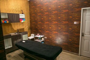 A room with a wooden wall, a bed, a sink, and a cabinet with towels. - Echelon Heights Hotel (Port Harcourt)