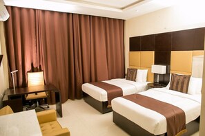 A hotel room with two beds, a desk, a chair, and a large window with curtains. - Echelon Heights Hotel (Port Harcourt)
