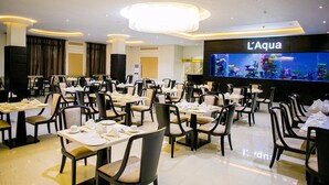 A restaurant with multiple tables and chairs, a large aquarium display, and a sign reading "L'Aqua". - Echelon Heights Hotel (Port Harcourt)