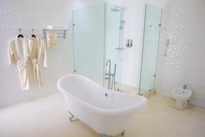 A modern bathroom with a freestanding bathtub, a glass-enclosed shower, a bidet, and a glass shelf with towels. - Echelon Heights Hotel (Port Harcourt)