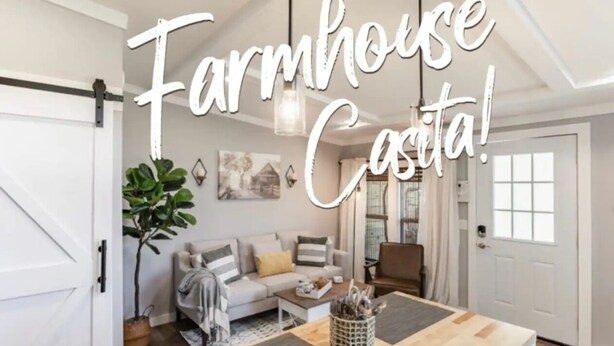 A farmhouse-style living room with a wooden dining table, a sofa, and a large plant.
