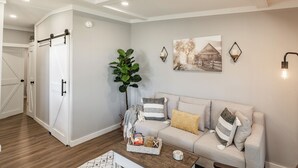 A cozy living room with a sofa, a coffee table, and a large plant.