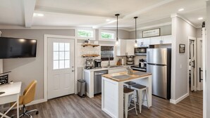A modern kitchen with a central island, stainless steel appliances, and a dining area with bar stools.