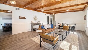 A spacious living area with a high wooden ceiling, a sofa set, a dining table, and a kitchen area in the background. - Spacious downtown apartment with parking (Douglas)