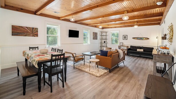 A spacious living area with a wooden ceiling, a dining table with chairs, a sofa, and a television mounted on the wall. - Spacious downtown apartment with parking (Douglas)