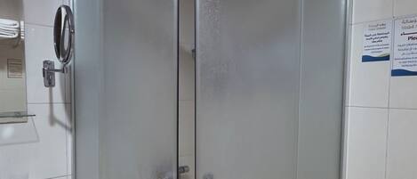 A glass-enclosed shower stall with a white sink and a mirror to the left.
