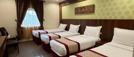 A hotel room with four beds, a desk, and a chair.