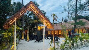 A beachside resort with thatched-roof structures, outdoor seating, and palm trees. - Wave Crest Retreat (Thulusdhoo Island)