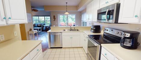 A kitchen with white cabinets, a stainless steel dishwasher, a black stove, and a microwave.
