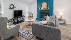 A living room with a television, two armchairs, a sofa, a coffee table, and a patterned rug. - 2BR Ensuite | Near UT & The Domain (Austin)