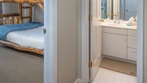 A room with a bunk bed, a bathroom with a sink and mirror, and a door leading to another room. - Spacious 4 bedroom condo in the heart of Vail Village, great value!! (Vail)