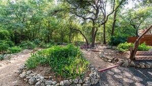 A garden area with a stone border, various plants, and trees. - Zilker Park, Town lake, and Barton Springs pool (Austin)