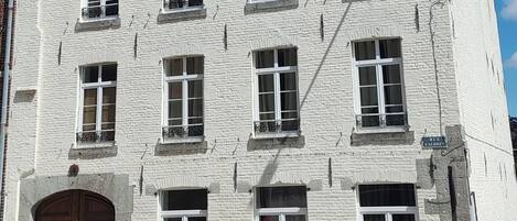 Un edificio de ladrillo blanco con varias ventanas y una puerta de madera.