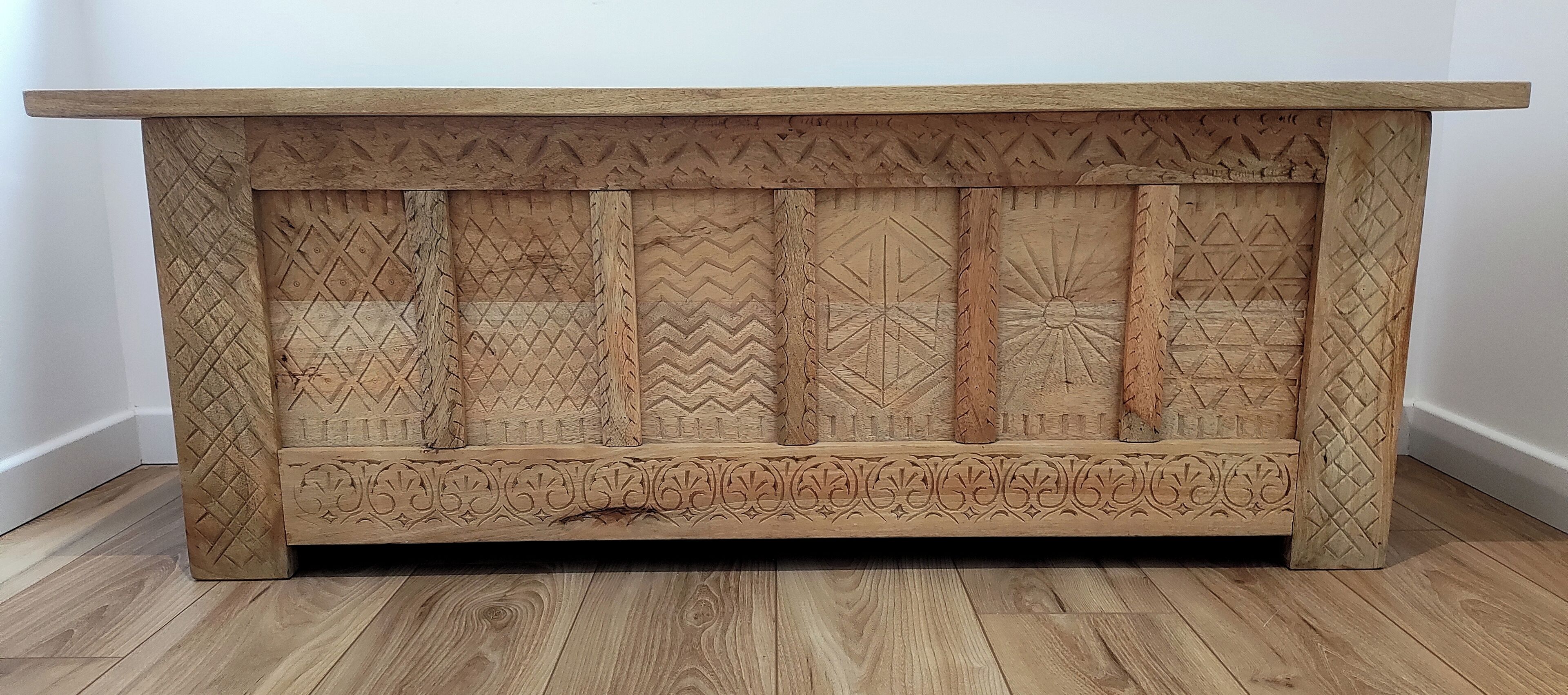 A wooden cabinet with intricate carvings and a flat top surface.
