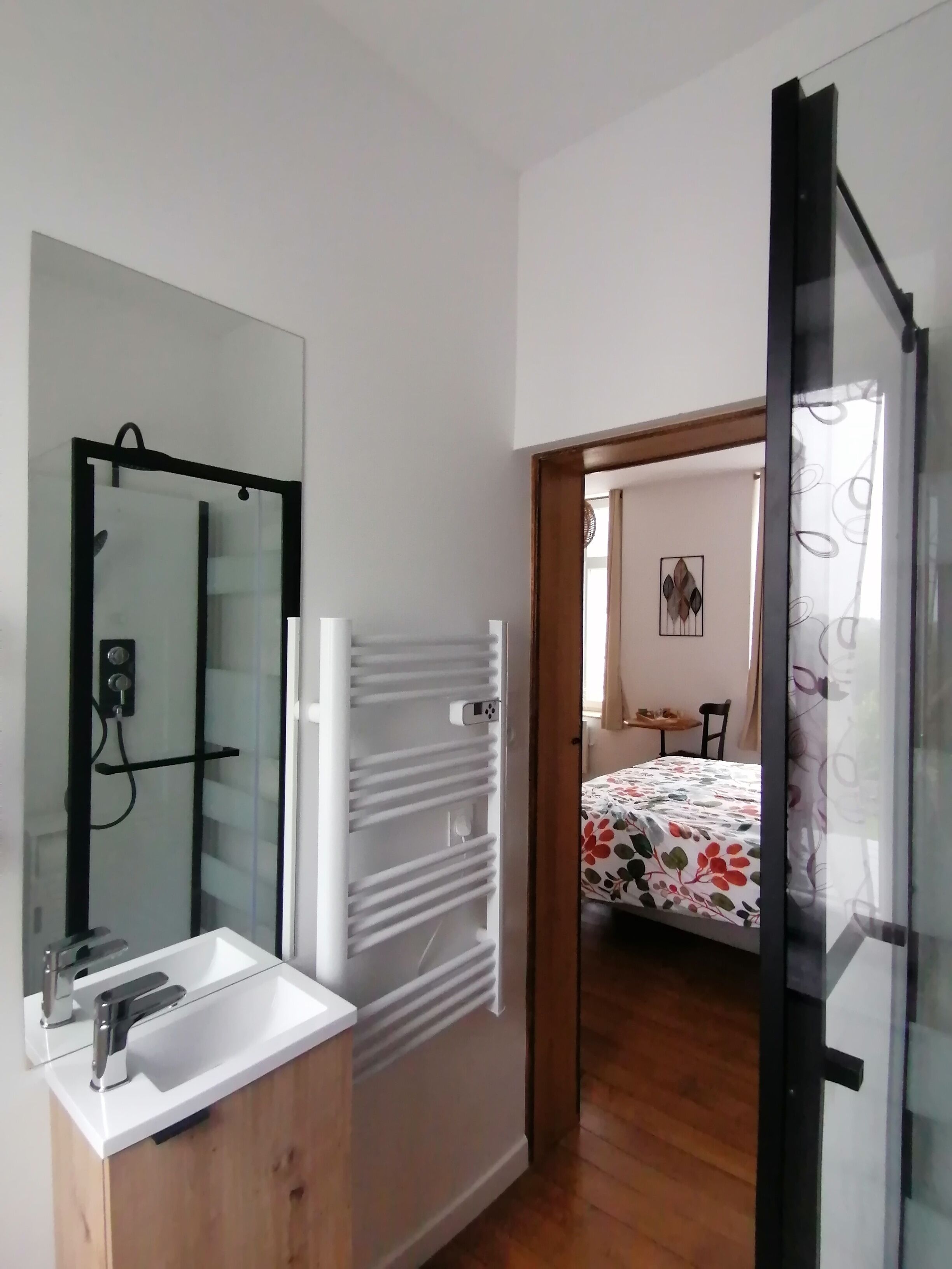 Une salle de bain moderne avec un lavabo blanc, un miroir et un porte-serviettes.