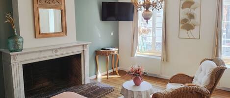 Una habitación acogedora con chimenea, sillones de mimbre, televisor y ventana con vistas.