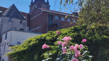 Ein historisches Gebäude mit einem markanten Turm und einem Rosengarten im Vordergrund.