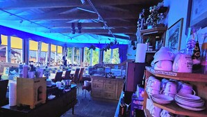 A cozy, dimly lit café with wooden furniture and a variety of mugs and plates displayed on shelves. - No1 - Flo's modern Rooms & Breakfast  (Wagrain)