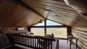 L’intérieur d’une cabane en rondins, avec un plafond en pente, un banc en bois, un canapé et une table.