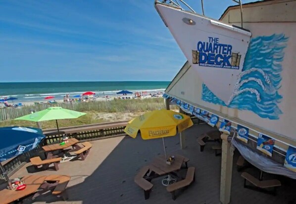 Un restaurant situé en bord de mer, appelé « The Quarter Deck », avec une terrasse et des parasols.