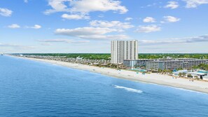 Un hôtel situé sur la côte, avec vue sur la plage, plusieurs piscines et un grand bâtiment central.