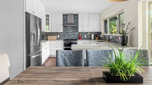 Una cocina moderna con armarios blancos, un refrigerador de acero inoxidable y una isla grande con asientos.