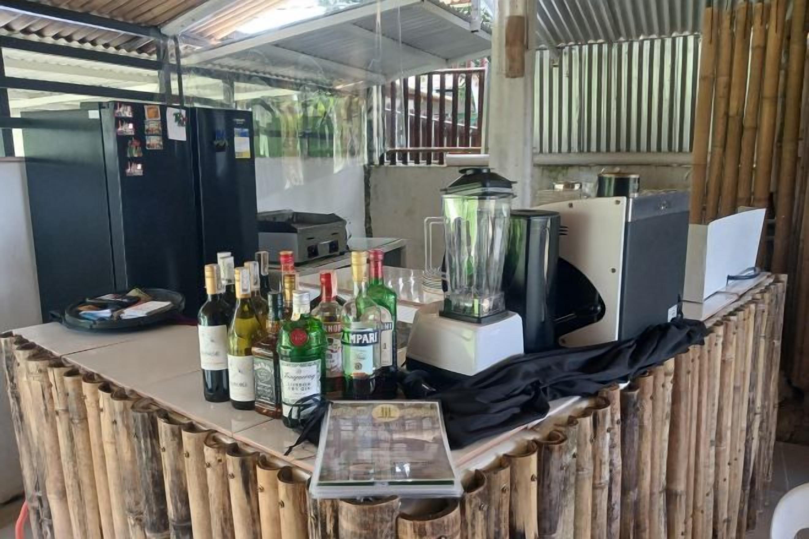 Zona de bar con mostrador, botellas, licuadora y refrigerador.