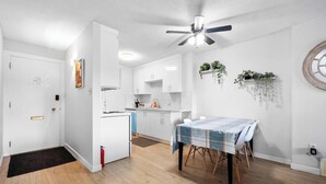 Eine moderne Küche mit weißen Schränken, einem Esstisch mit Tischdecke und einem Deckenventilator.