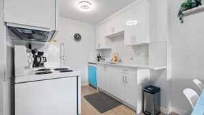 Eine moderne Küche mit weißen Schränken, einem Backofen, einem Geschirrspüler und einer Uhr an der Wand.