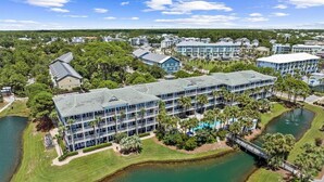 A resort with multiple buildings, a central pool, and a lake.