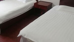 Une chambre d’hôtel avec deux lits, une table de chevet en bois et une commode rouge.