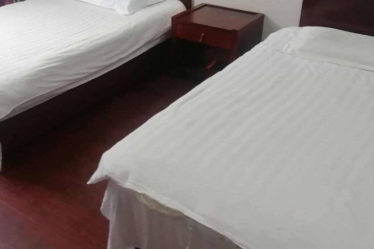 Ett hotellrum med två sängar, ett nattduksbord i trä och en röd byrå.