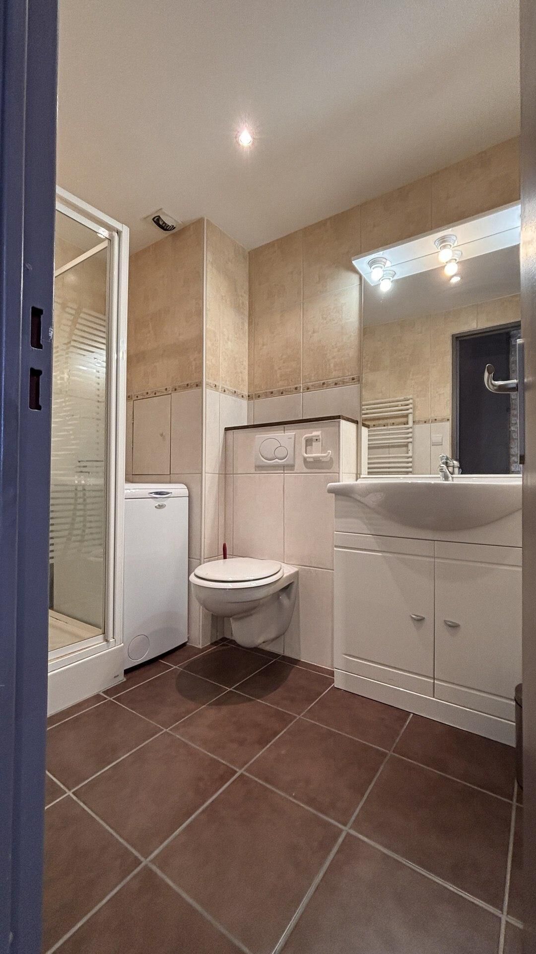 A compact bathroom with a toilet, a sink, and a shower enclosure.