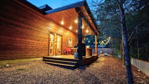 A wooden cabin with a covered porch, steps leading to the entrance, and a grill outside. - Woodland Family Retreat Near the Lake (Broken Bow)