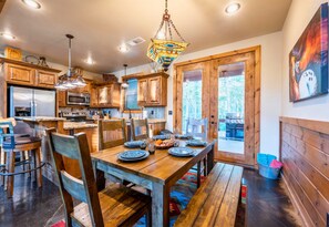 Une cuisine moderne avec des meubles en bois, des appareils en acier inoxydable et un coin repas comprenant une table et des chaises en bois.