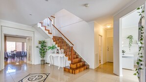 Un vaste espace de vie agrémenté d’un escalier en bois, un coin repas avec une table et des chaises, et un mur blanc orné d’une plante.