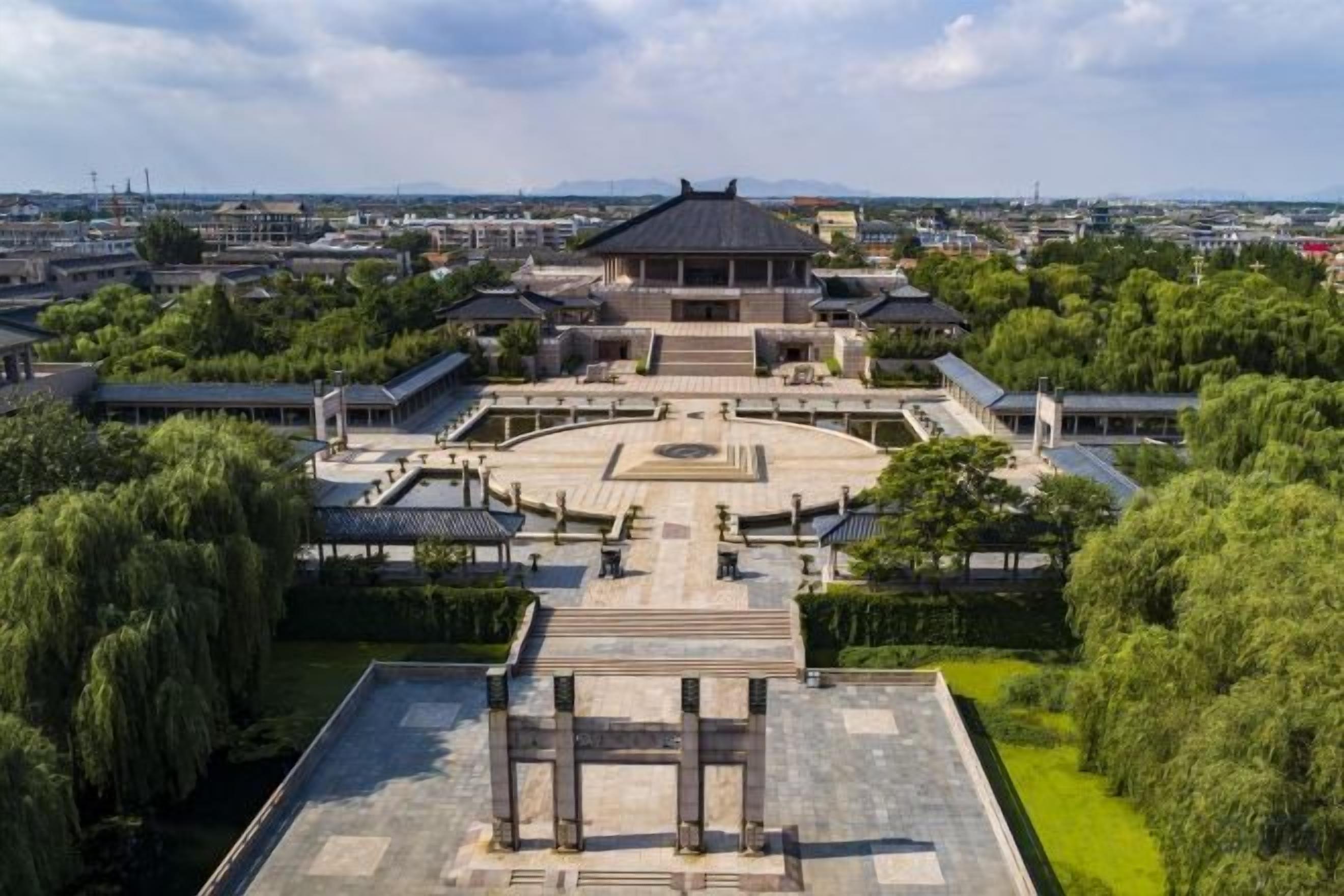 A traditional building with a circular courtyard, surrounded by trees and a flat-roofed structure.