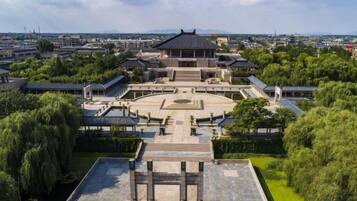 A traditional building with a circular courtyard, surrounded by trees and a flat-roofed structure.