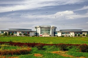 A modern building with a central dome and two wings, surrounded by a green field. - Magnotel Hotel (Qufu Sankong Scenic Area Chunqiu West Road) (Qufu)