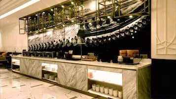 A modern bar area with marble countertops, overhead lighting, and a long counter.