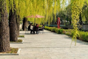 An outdoor seating area with tables and chairs, surrounded by trees and a pathway. - Magnotel Hotel (Qufu Sankong Scenic Area Chunqiu West Road) (Qufu)