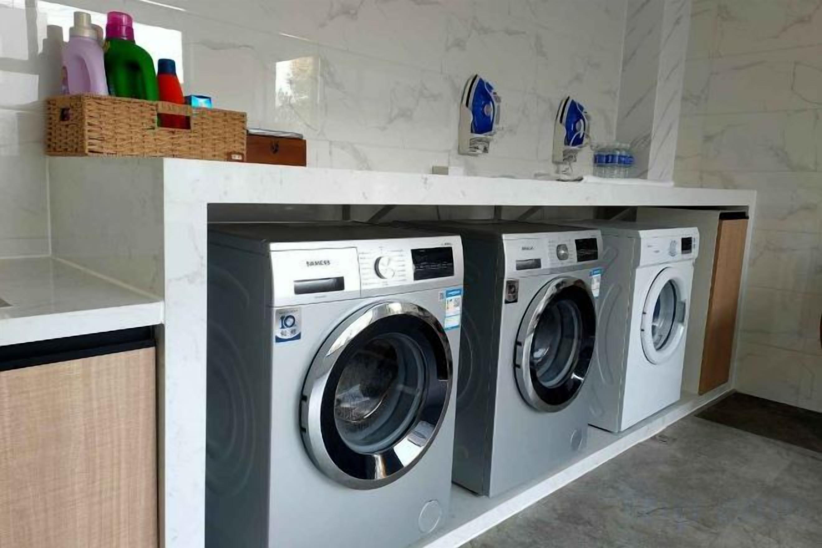 A laundry area with two front-loading washing machines, a white countertop, and a marble backsplash.