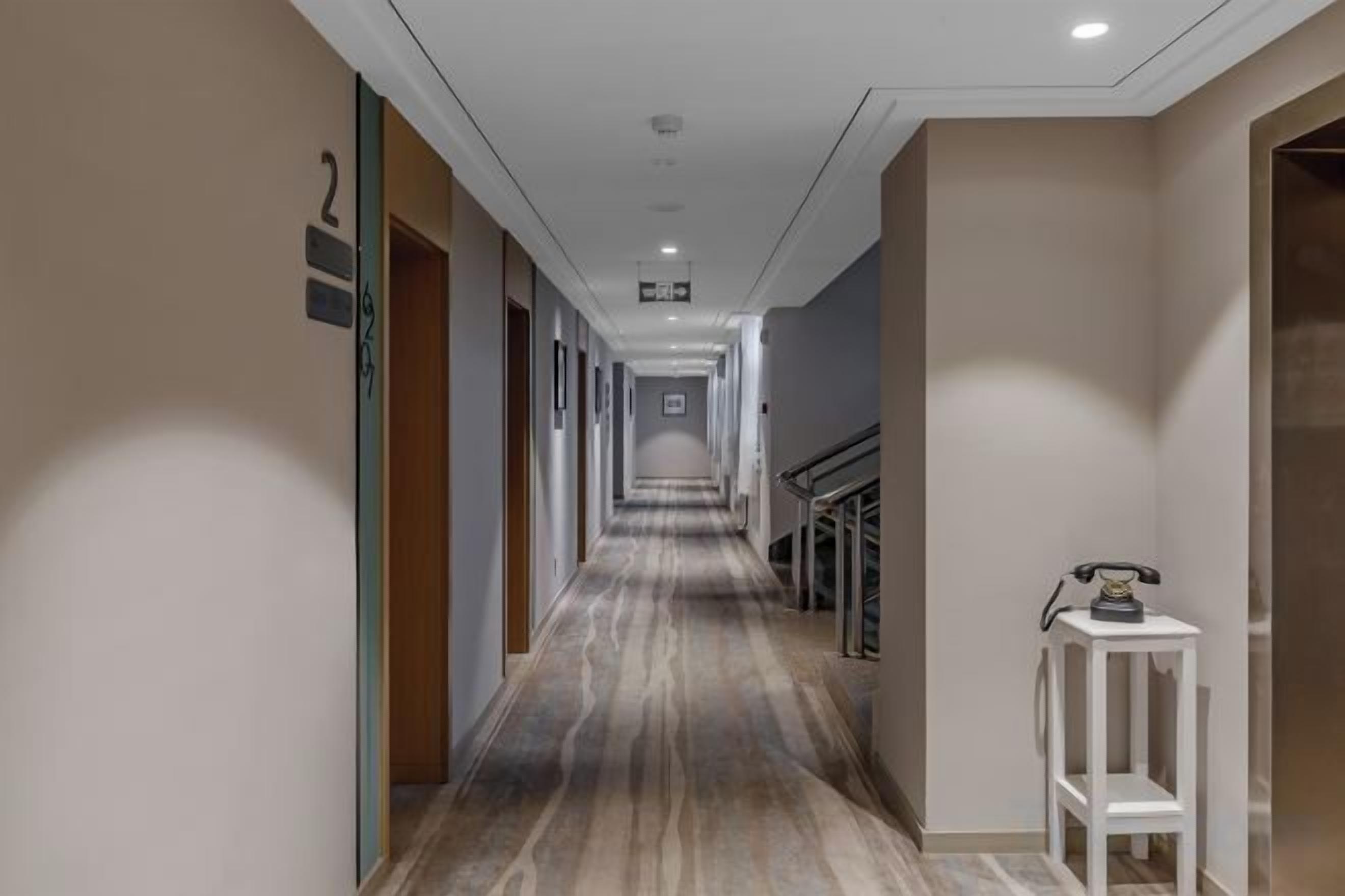 A hotel corridor with a marble floor, a reception desk, and a staircase.